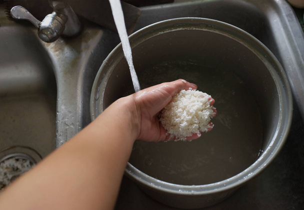 vue du dessus femme de ménage un riz à laver, tremper le riz, dans la cuisinière à riz, l'eau versant dans le riz dans la cuisine nettoyage et préparation des aliments, cuisine ou cuisinière électrique fond avec échelle  - Photo, image
