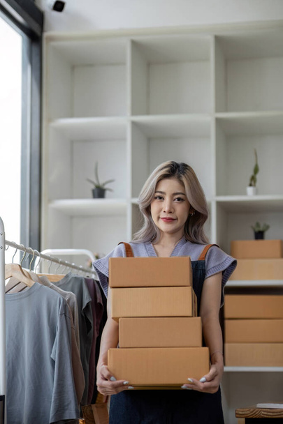 Koncepcja biznesowa online, azjatyckie kobiety biznesu posiada skrzynki paczek produktu do dostawy do klienta. - Zdjęcie, obraz
