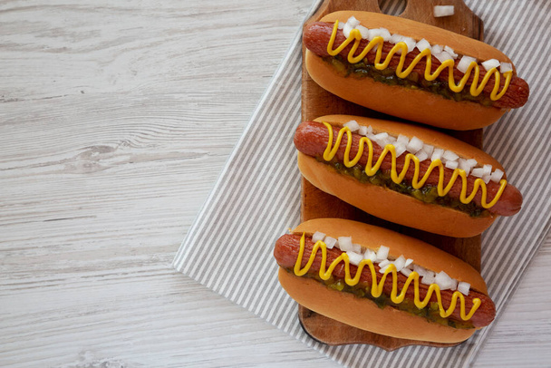Char Grilled Hot Dog met Mustard, Relish en Ui op een rustieke houten plank, bovenaanzicht.  - Foto, afbeelding