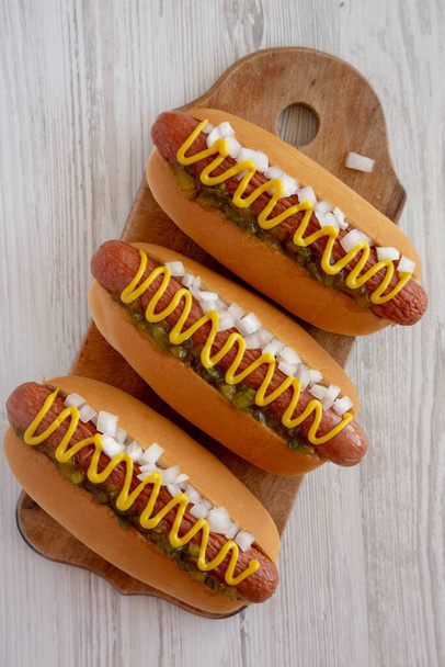 Char Grilled Hot Dog met Mustard, Relish en Ui op een rustieke houten plank, bovenaanzicht.  - Foto, afbeelding