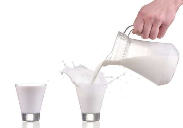 Gieten van melk uit kruik fles in een glas met splash op witte achtergrond - Foto, afbeelding