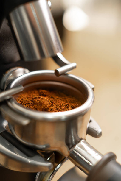 Close-up van vers gemalen koffiebonen in een portafilter bij de koffiemolen. Kopieerruimte - Foto, afbeelding