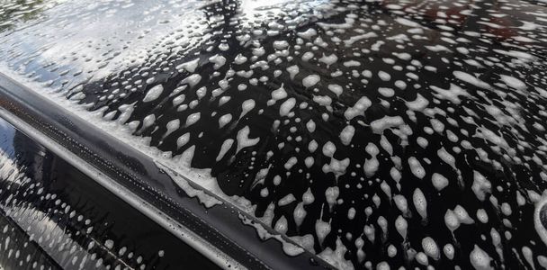 Car wash. Foam on the car in the carwash. Cleaning the car. - Photo, Image