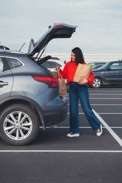 smiling woman put bags in car trunk groceries shopping - Photo, Image