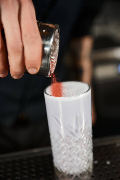 abgeschnittene Ansicht des Barkeepers, der Zimt im Glas mit Milchpunsch hinzufügt, Cocktailzubereitung im Bar-Ambiente - Foto, Bild
