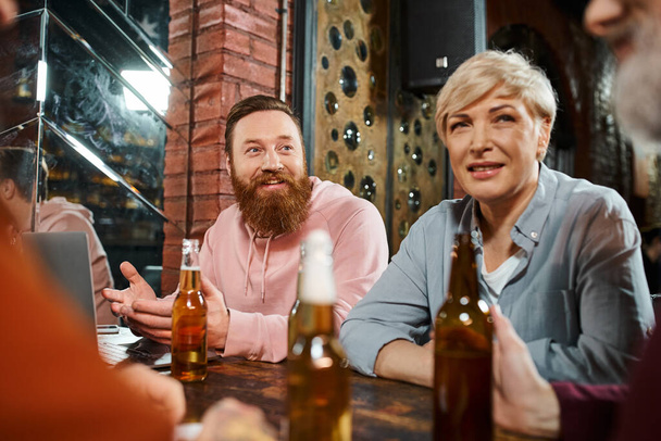 hombre barbudo emocionado hablando y compartiendo la idea de colegas de negocios sentados en el pub después del trabajo - Foto, Imagen