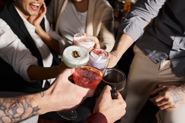 przycięty widok wielonarodowych kolegów brzęczących szklankami z pysznymi koktajlami w barze, czas na zabawę - Zdjęcie, obraz