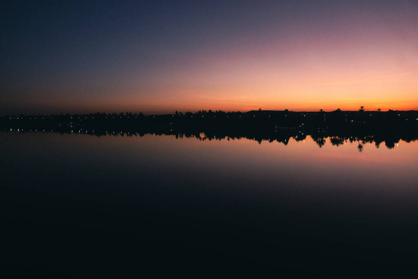 Dawn's Embrace: Serene Nile River Sunrise from the Cruise Ship. Foto di alta qualità Trova la beatitudine nella serenità di un'alba egiziana sulle acque calme del fiume Nilo, il tutto dal punto di vista del ponte di una nave da crociera. Questa immagine incapsula t - Foto, immagini