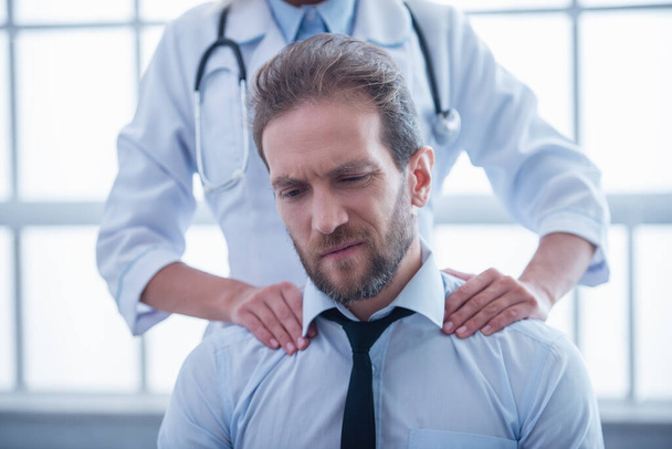 Bela médica está fazendo sua paciente uma massagem
 - Foto, Imagem