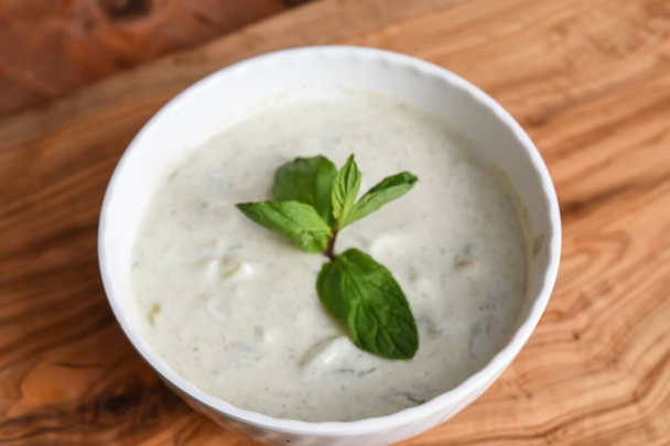 Knoblauch Minze Joghurt serviert in Schale isoliert auf hölzernen Tischplatte Ansicht nahöstlichen Vorspeisen Essen - Foto, Bild