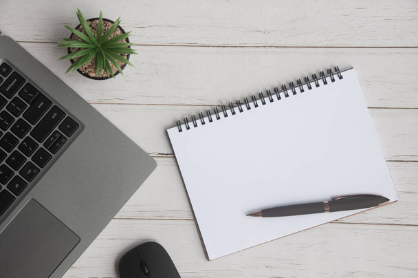 Bovenaanzicht van laptop, tafelplant, blanco notitieblok en muis op witte omslag achtergrond met aanpasbare ruimte voor tekst. Kopieerruimte - Foto, afbeelding