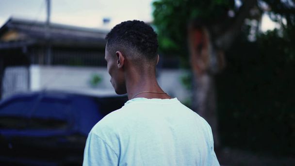 Pewien zamyślony czarny człowiek idący ulicą w głębokim umysłowym odbiciu i zmartwionych emocjach. Tracking motion shot Brazylijczyka spacerującego w środowisku miejskim - Zdjęcie, obraz