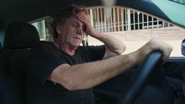 Один пригнічений старший чоловік, який страждає від психічних захворювань всередині транспортного засобу, тримається за кермо автомобіля, автомобільний інтер'єр літньої кавказької людини в тяжких умовах - Фото, зображення