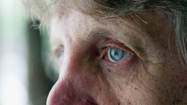 Makro-Nahaufnahme eines nachdenklichen älteren Mannes mit blauen Augen, die leere Mienen starren, nachdenkliche Emotionen älterer Menschen, Ausdruck Alter und Weisheit - Foto, Bild