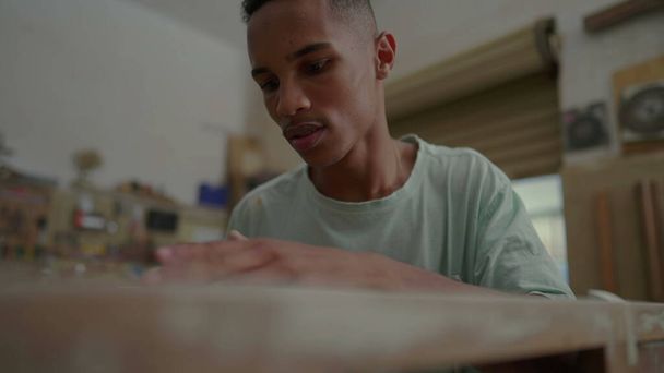 Фокусований молодий працівник полірує дерев'яні меблі в столярній майстерні, займається ремонтом малого бізнесу - Фото, зображення