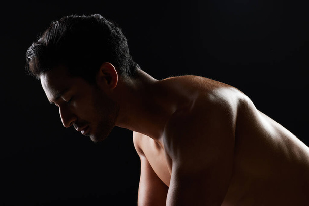Exercise, strong and studio man doing push up challenge, gym fitness routine and workout for muscle building. Dark shadow light, body training development and calm sports athlete on black background. - Photo, Image