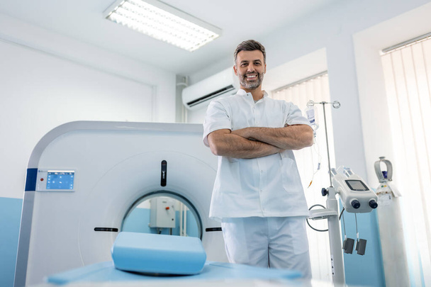 Magabiztos férfi orvos onkológia mágneses rezonancia képalkotó vagy komputertomográfia szoba egy modern kórház. - Fotó, kép