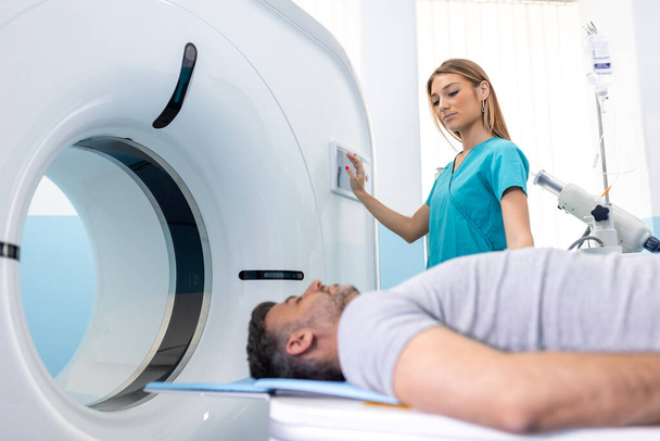 Vrouwelijke dokter kijkt naar patiënt die CT-scan ondergaat. Arts in uniform met tomografie machine met liggende patiënt in het ziekenhuis - Foto, afbeelding