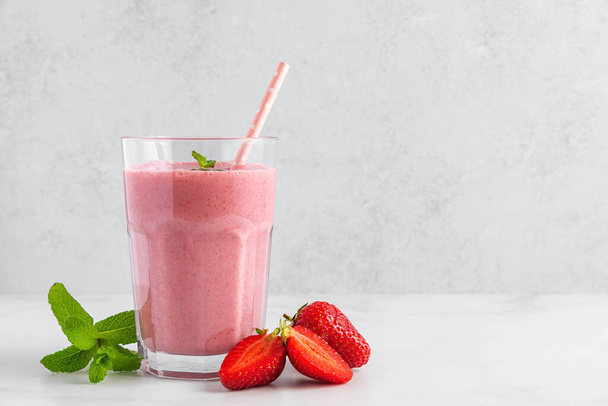 Erdbeer-Smoothie im Glas mit Stroh, frischen Beeren und Minze. Sommer-Erfrischungsgetränk. Gesunde Ernährung. - Foto, Bild