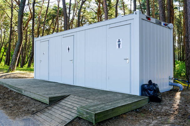 Сучасний громадський метал три туалетні контейнери з дерев'яною терасою в приморському парку, поліпшення екології - Фото, зображення