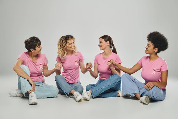 felice interrazziale donne età diversa che si tengono per mano su sfondo grigio, la consapevolezza del cancro al seno - Foto, immagini