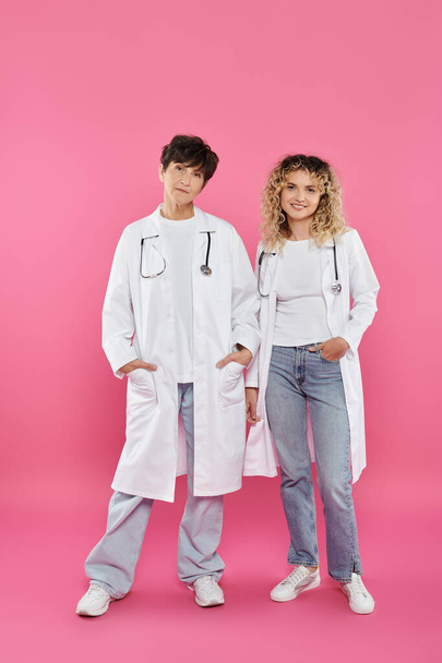 alegres médicos do sexo feminino em casacos brancos em pé no fundo rosa, alegria, consciência do câncer de mama, mulheres - Foto, Imagem