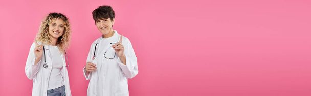 doctores con batas blancas advirtiendo sobre el telón de fondo rosa, alegría, conciencia sobre el cáncer de mama, mujeres, pancarta - Foto, Imagen