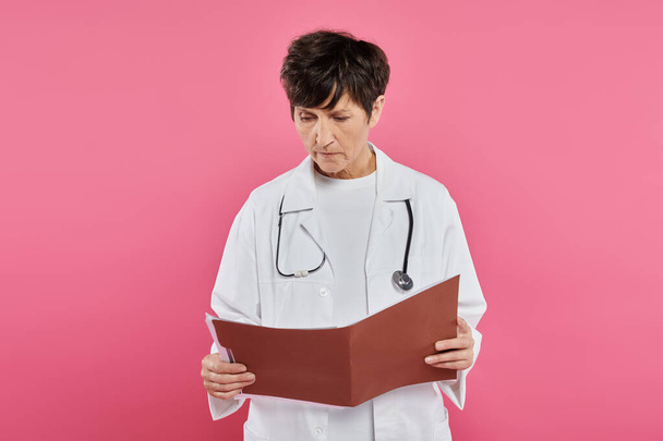 Onkologin mittleren Alters, Ärztin betrachtet Folder, Brustkrebs-Aufklärungskonzept, Diagnose - Foto, Bild