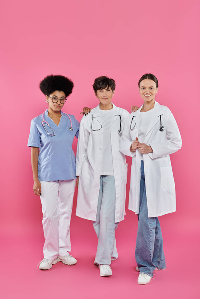 Onkologen, drei interrassische Ärztinnen, Brustkrebs-Aufklärung, Früherkennung, Kampagne - Foto, Bild