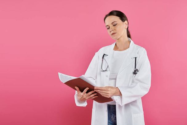 emlőrák tudatosság, női orvos, orvosi leletet olvasó onkológus, mappa, rózsaszín háttér - Fotó, kép