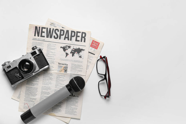 Newspaper with microphone, photo camera and eyeglasses on white background - Photo, Image