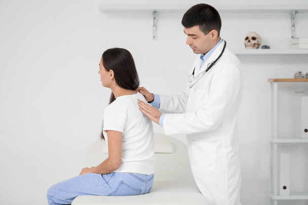 Médico varón comprobando postura de mujer joven en clínica - Foto, imagen