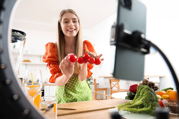 Женщина-блоггер с помидорами запись приготовления видео на кухне - Фото, изображение