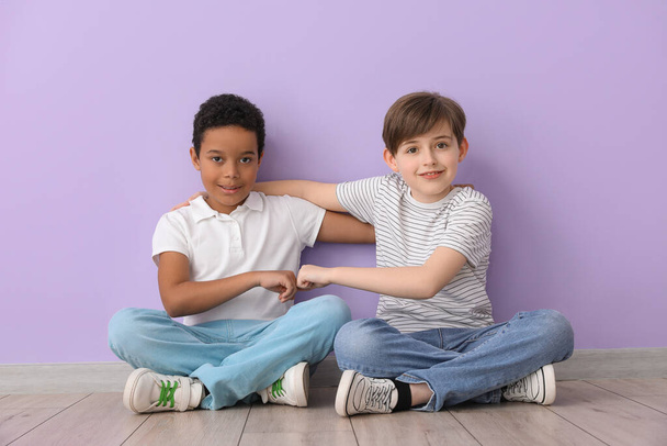 carino piccoli ragazzi abbracciare vicino lilla muro - Foto, immagini