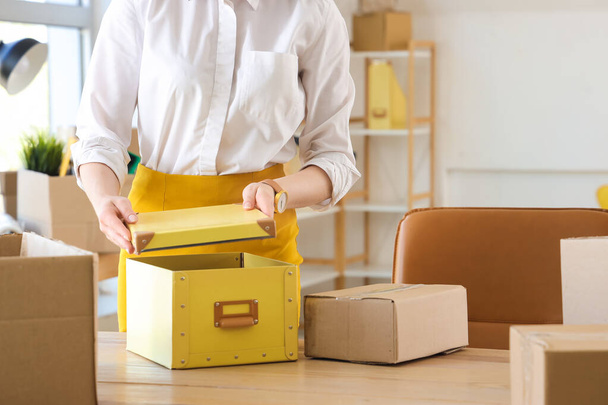 Businesswoman packing belongings into box on moving day - Photo, Image