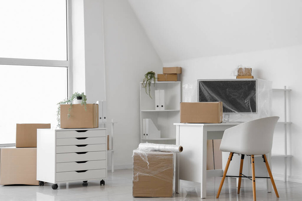 Интерьер светлого офиса с картонными коробками и стретч-пленкой в день переезда - Фото, изображение