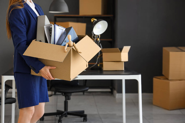 Деловая женщина держит картонную коробку с вещами в офисе в день переезда - Фото, изображение