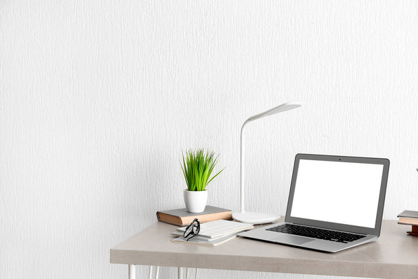 Comodo posto di lavoro con computer portatile moderno, libri e piante d'appartamento su tavolo beige - Foto, immagini