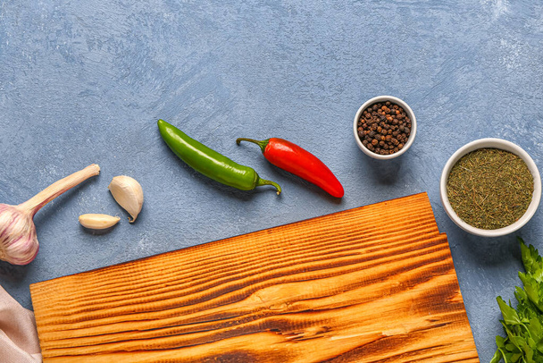 Σύνθεση σαλονιού με ξύλινη σανίδα κουζίνας και διάφορα μπαχαρικά σε φόντο χρώματος - Φωτογραφία, εικόνα