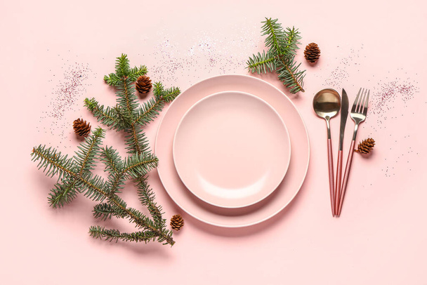 Joulukuusen kattaus kuusen oksilla, käpyillä, lautasilla ja ruokailuvälineillä vaaleanpunaisella pohjalla - Valokuva, kuva