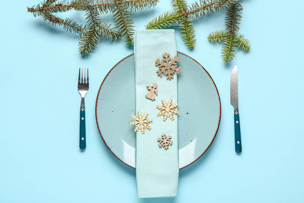 Joulupöydän kattaminen lautasella, lautasliinalla, ruokailuvälineillä ja kuusen oksilla sinisellä pohjalla - Valokuva, kuva