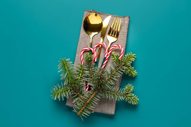 Lautasliina joulukuusen oksat, kultainen ruokailuvälineet ja karkkia keppejä sinisellä pohjalla - Valokuva, kuva