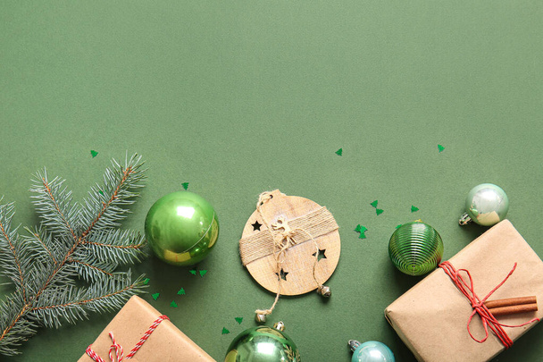 Гілка ялинки з кульками та подарунковими коробками на зеленому фоні - Фото, зображення