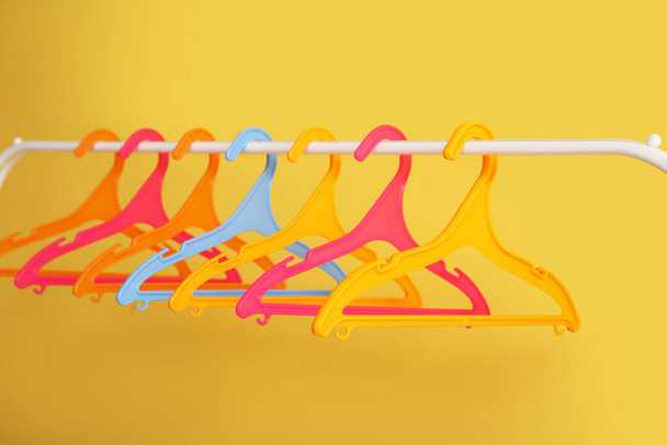 Стелаж з пластиковими вішаками для одягу на жовтому тлі - Фото, зображення