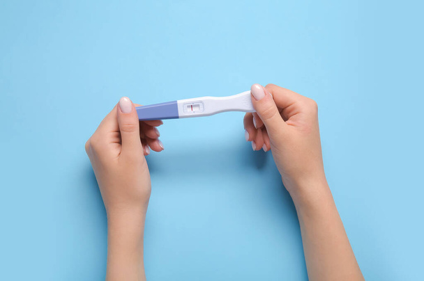 Mani femminili con test di gravidanza negativo su sfondo colore - Foto, immagini