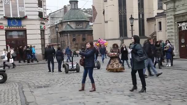 LVIV, UCRANIA - 28 de febrero de 2015 Lviv plaza central ocupada con peatones a pie y en tranvía
 - Metraje, vídeo