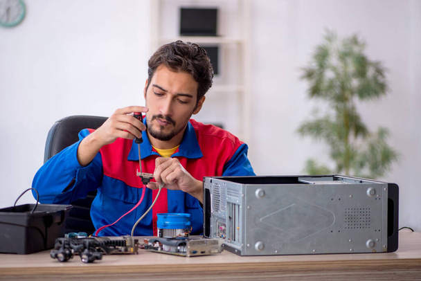 Junger Reparateur repariert Computer in Werkstatt - Foto, Bild
