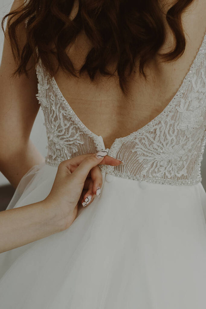 jong blank meisje zippen trouwjurk op de achterkant van de bruid, close-up uitzicht van de zijkant. - Foto, afbeelding