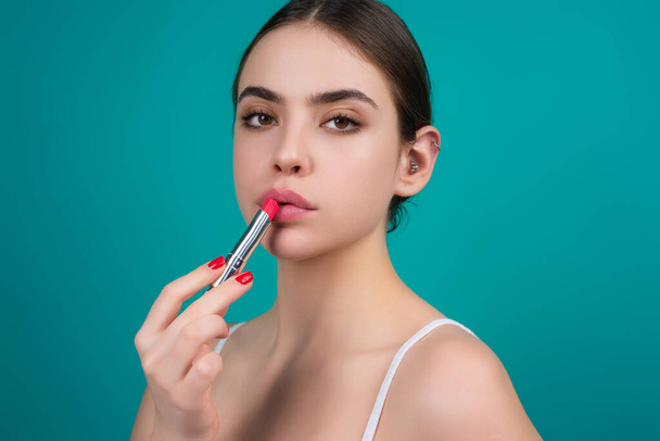 Sexy girl use lipstick, background beauty and fashion, lips appreciation concept. Plump woman lips, isolated on blue studio background - Photo, Image