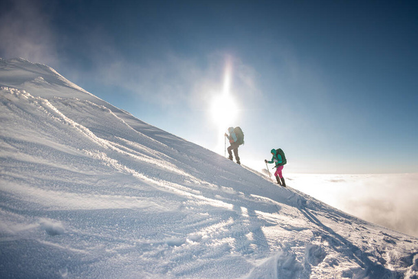 Két hegymászó mászik fel a hegyre. Két lány mászik fel egy hóval borított hegyre. téli hegymászás. - Fotó, kép